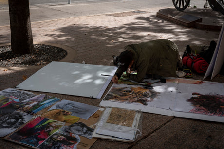 a man is painting pictures on a sidewalk